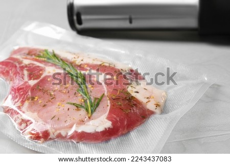 Sealer for vacuum packing with plastic bag of meat on light grey table, closeup Royalty-Free Stock Photo #2243437083