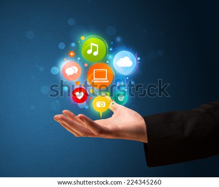 Young businessman holding colorful multimedia icons in his hand