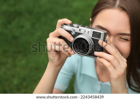 Young woman with camera taking photo outdoors, space for text. Interesting hobby