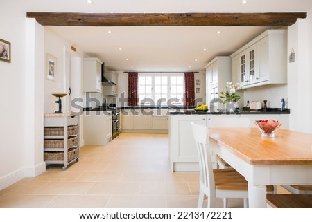 Open plan farmhouse kitchen dining room, with modern painted wood modular kitchen units, UK interior design Royalty-Free Stock Photo #2243472221
