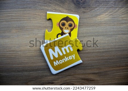 Yellow knowledge puzzle with monkey image and monkey text placed on wooden background.