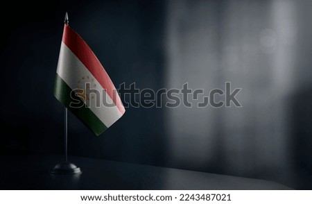 Small national flag of the Tajikistan on a black background.