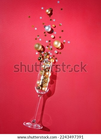 Glass with New Year decoration and serpentine on red background. Holidays concept