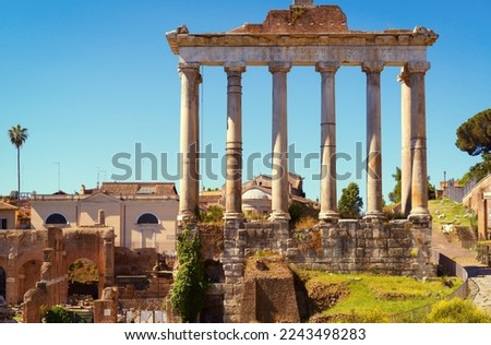 Ancient Temple of Saturn in Roman Forum, Rome, Italy, Europe. It is landmark of Rome. Old columns rise over Forum ruins and city buildings in Roma center. Concept of travel in Rome, history, culture