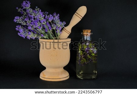 Lavender oil in glass bottle near fresh lavender flowers on black background