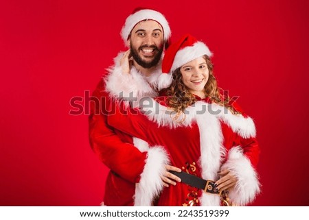 Brazilian couple, dressed in Christmas clothes, Santa Claus, hugging, giving kiss