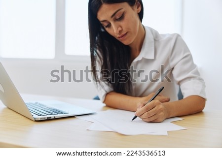 A woman works and learns by writing down text on paper with a pen and checking for errors, studying and teaching in college, business work