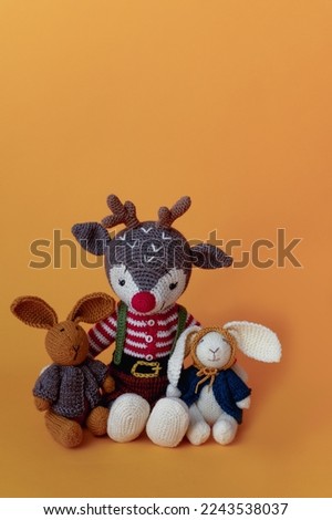 funny knitted children's toy deer and two rabbits on an isolated yellow background. High quality photo