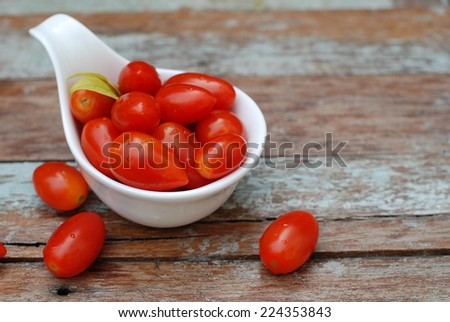 cherry tomatoes in a cup on wooden background.