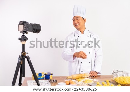 male chef food vlogger shooting video while making cake dough on table with isolated background