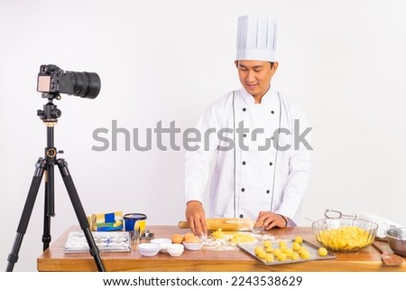 male chef food vlogger using wooden rolling pin on table while baking cake on isolated background