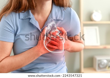 Young woman pressing on chest with painful expression. Severe heartache, having heart attack or painful cramps, heart disease. Royalty-Free Stock Photo #2243547321