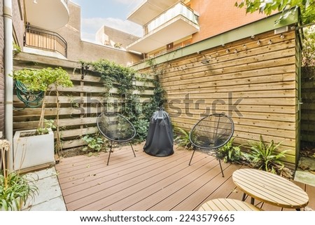 a backyard area with wooden decking and plants on the wall, two chairs and a table in the corner