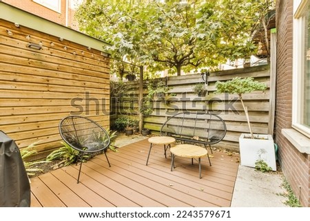 a backyard area with two chairs and a table on the deck, surrounded by a wooden fence that's made out of wood
