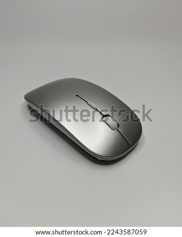 modern wireless computer mouse bright gray color with white scroll on a white floor artificial lighting