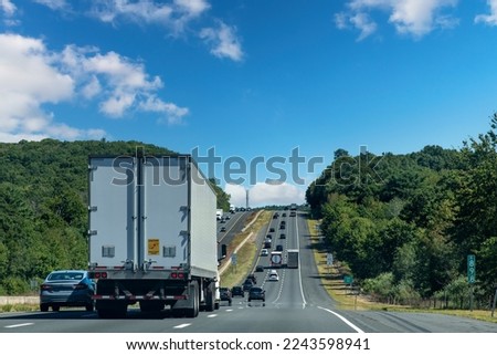 Drivers perspective view over busy and hilly Interstate 84 highway in northerly direction near Willington, CT, USA with trucks and cars on highway Royalty-Free Stock Photo #2243598941