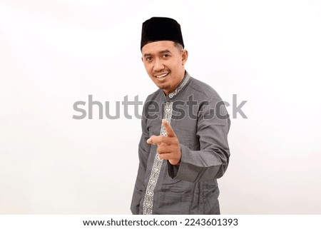 Happy asian muslim man standing while pointing at the camera. Isolated on white background
