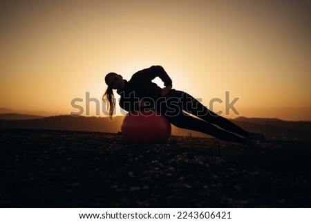 Young woman practicing yoga in the sunset in a beautiful landscape surrounded by mountains. Healthy lifestyle concept. 