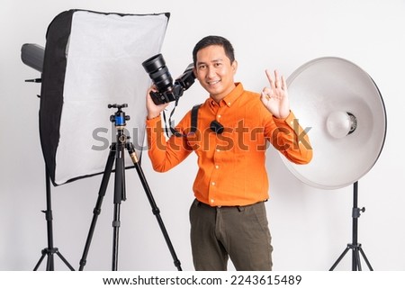 smiling man holding dslr camera with okay hand gesture on isolated background