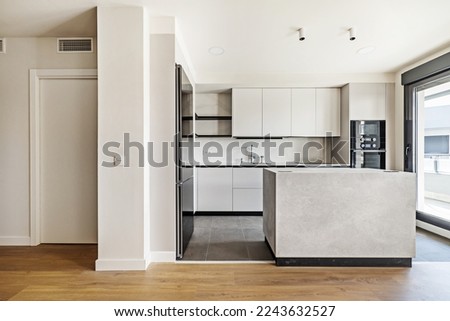 Front of a recently installed modern style kitchen with handleless cabinets, marble island and stoneware floors combined with laminated flooring with access to a glazed terrace