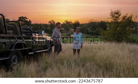 Asian women and European men on safari game drive in South Africa Kruger national park. a couple of men and women on safari. Tourists in a jeep looking sunset with drinks on safari Royalty-Free Stock Photo #2243675787