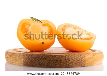 Two halves of a juicy yellow tomato, close-up, on a wooden tray on a white background.