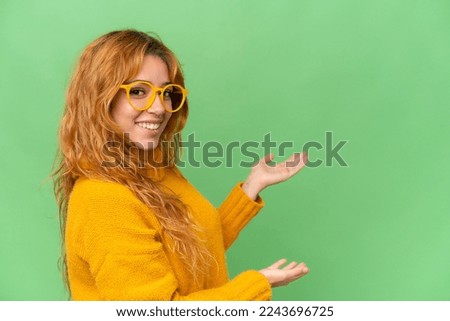 Young caucasian woman isolated on green screen chroma key background With glasses and presenting something