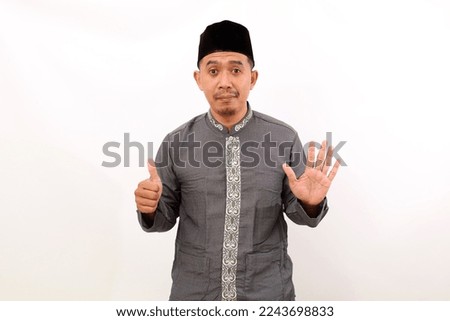 Happy asian muslim man standing while showing six fingers. Isolated on white background
