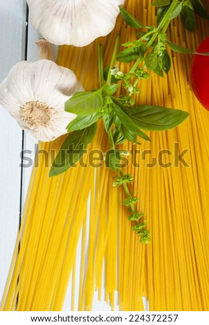 spaghetti, basil leaves, tomatoes and other italian food ingredients on white wooden 
