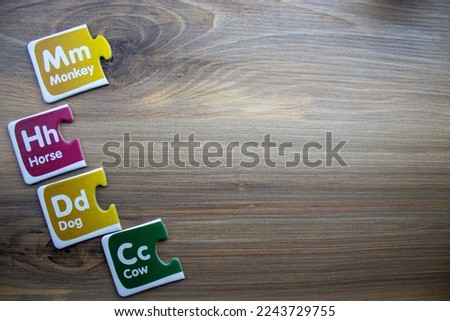 Knowledge puzzles with inscriptions monkey, horse, dog and cow placed on wooden background.