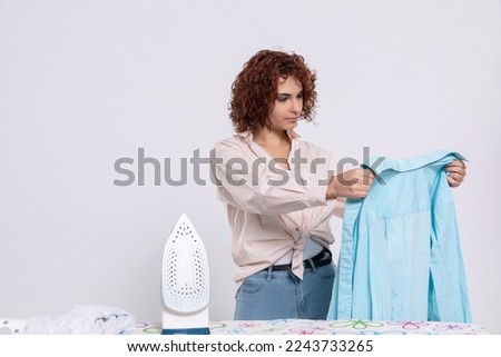 Before ironing, the girl carefully inspects the shirts.