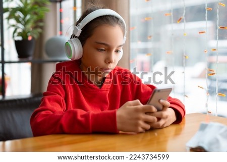 Photo of a teenager girl in a white headphones during online chatting with friends. Modern technology concept.