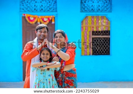 Happy Indian farmer with wife and daughter making home shape with hand. dream home concept. Royalty-Free Stock Photo #2243755029