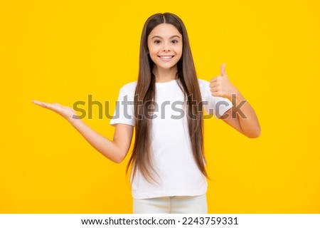 Wow, it's unbelievable. Shocked teenager child pointing aside at copy space. Teen girl pointing with two hands and fingers to the side. Happy teenager portrait. Smiling girl.