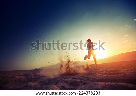Young lady running in the desert at sunset Royalty-Free Stock Photo #224378203