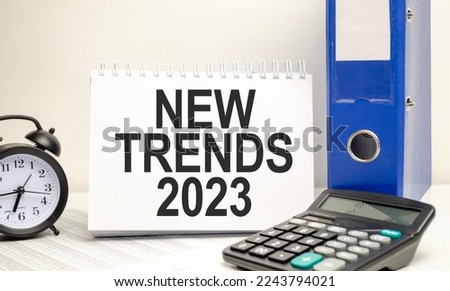 white notebook with the text TRENDS 2023 with calculator and paper folder