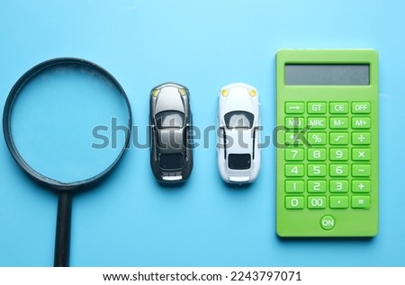 Flatlay picture of magnifying two cars diorama miniature and calculator. Best deal car to drive.
