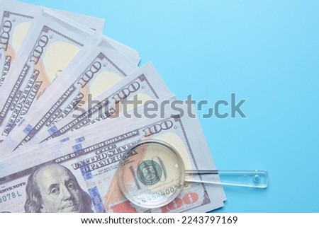 Flatlay picture of fake cash with magnifying glass on copyspace background. Financial solution concept.