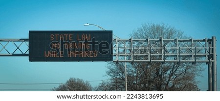 An overhead highway sign reminds drivers that driving under the influence is illegal. Royalty-Free Stock Photo #2243813695