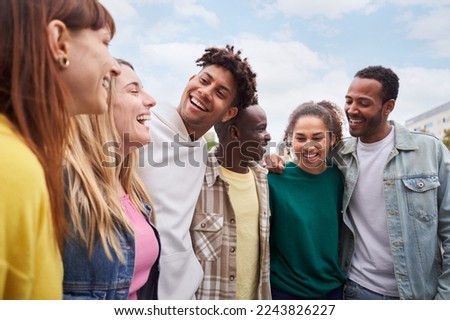 Young people walking laughing Happy friendship group of mixed race people cheerful together outdoors. Smiling students having fun during a travel trip. Multi-ethnic men and women hugging at the city Royalty-Free Stock Photo #2243826227