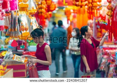 Asian woman mother and daughter holding shopping bag during buy home decorative ornament for celebrating Chinese Lunar New Year festival at Bangkok Chinatown street market. Chinese culture concept. Royalty-Free Stock Photo #2243841207