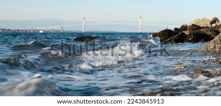 Wavy rocky seashore with bridge in background