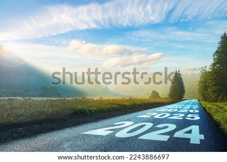 road on which is written 2024 at sunrise in the mountains ilis.beginning 2024. morning fog near the forest and mountains and road. 2025. 2026. 2027. 2028. Royalty-Free Stock Photo #2243886697