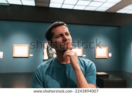 a bored and dissatisfied man visitor or student in an art gallery or museum looks at the masterpieces of classical artists Royalty-Free Stock Photo #2243894007
