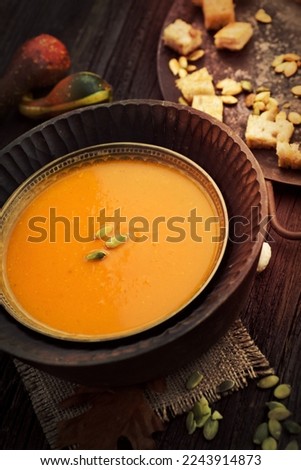 Vegetarian food concept. Pumpkin soup with pumpkin seeds, croutons and garnish on wooden background
