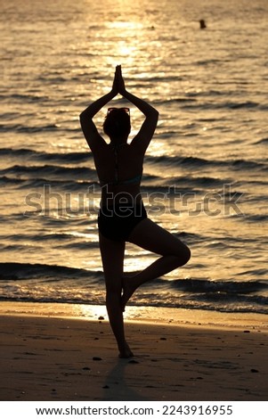 Woman having yoga meditation on beach at sunset. Silence and relaxation concept. 