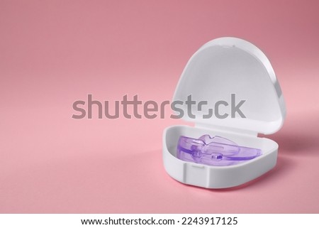 Transparent dental mouth guard in container on light pink background, space for text. Bite correction Royalty-Free Stock Photo #2243917125