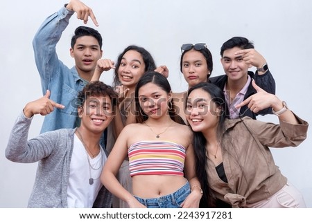A group of seven happy and young people in their late teens to early 20s pointing to their friend in the middle. Presentation and advertising concept. Isolated on a white backdrop. Royalty-Free Stock Photo #2243917281