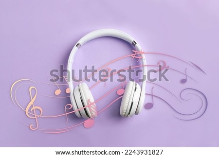 Staff with music notes and treble clef flowing over white headphones on lavender background, top view