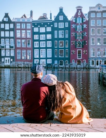 Amsterdam Damrak during sunset, happy couple man and woman on a winter evening at the canals Amsterdam at winter